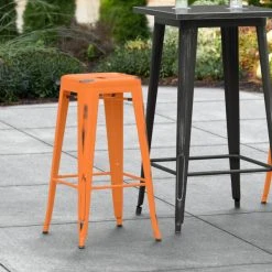 LT&S Alloy Series Lancaster Table & Seating Alloy Series Distressed Orange Stackable Metal Indoor / Outdoor Industrial Barstool With Drain Hole Seat
