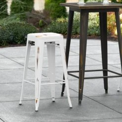 LT&S Alloy Series Lancaster Table & Seating Alloy Series Distressed White Stackable Metal Indoor / Outdoor Industrial Barstool With Drain Hole Seat